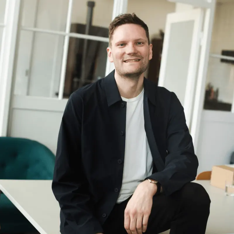 Michael Liepke Kruse sidder på et bord og smiler